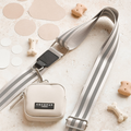 A stylish beige and gray striped dog leash is paired with the Reflective Bag Strap in Nude from Cocopup London, perfect for dog walking. The small beige carrying pouch, also labeled "Cocopup London," completes the set. Dog bone-shaped treats and round cutouts scattered around the leash and pouch on a light beige surface ensure both safety and style.