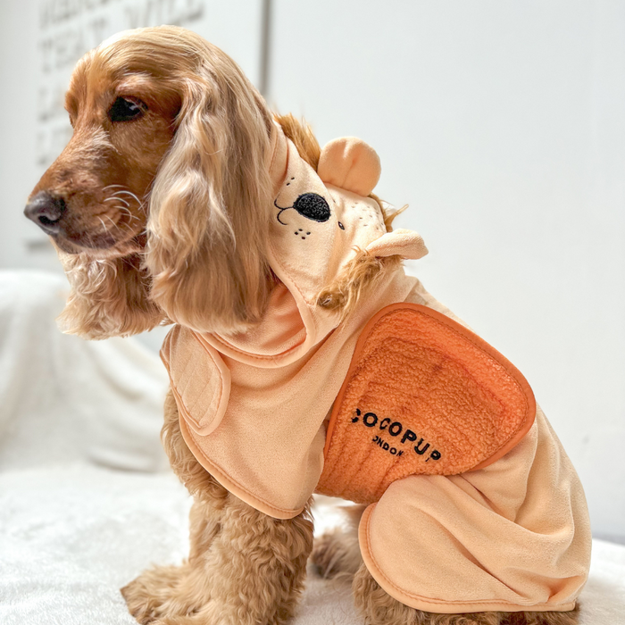 Brown dog wearing a Cocopup London Roary the Lion brown drying robe with lion hood, sitting on a white surface.