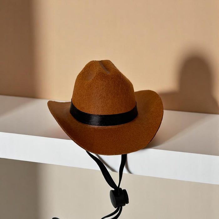 Tan Cocopup London Rodeo Pup dog hat with black band and chin strap displayed on a white shelf.