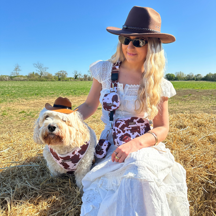 Woman and dog in tan cowboy outfits with Cocopup London Rodeo Pup Dog Hat, sitting together on a hay bale.