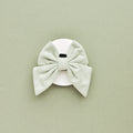 Sage tweed sailor bow tie with black center, displayed on white background and matching sage green surface.