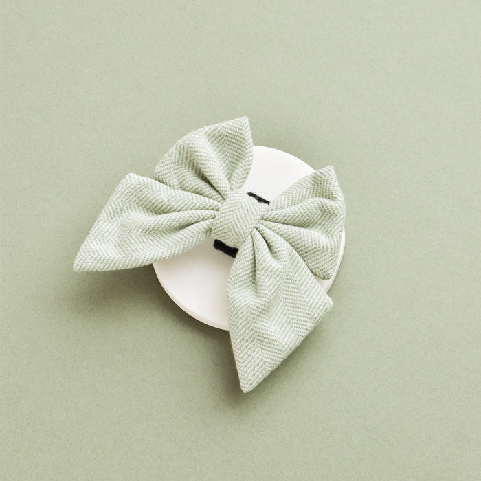 Sage green tweed sailor bow tie for dogs displayed on a white surface with a light green background.