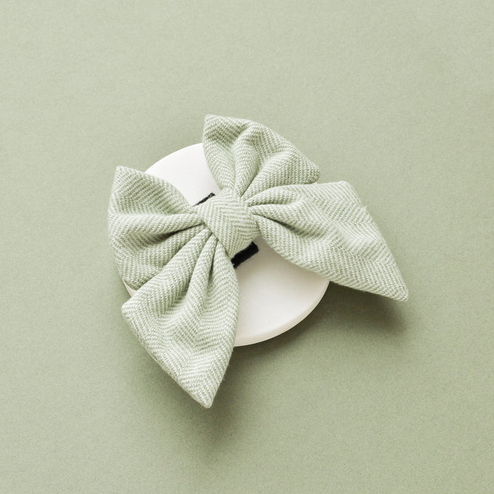 Sage green tweed sailor bow tie from Cocopup London displayed on a white circular background.