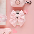 Baby pink heart-patterned sailor bow tie displayed with pink accessories and paper hearts on a pink background.