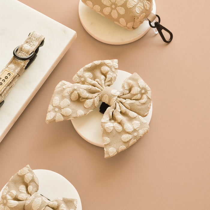 Mocha flower-patterned Luxe Sailor Bow Tie by Cocopup London on a round platform, beige background.