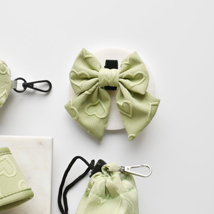 Sage green sailor bow tie with heart pattern on a white surface, next to matching accessories.