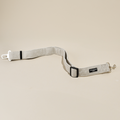Brown tweed Cocopup London seat belt restraint with metal clips on a beige background.