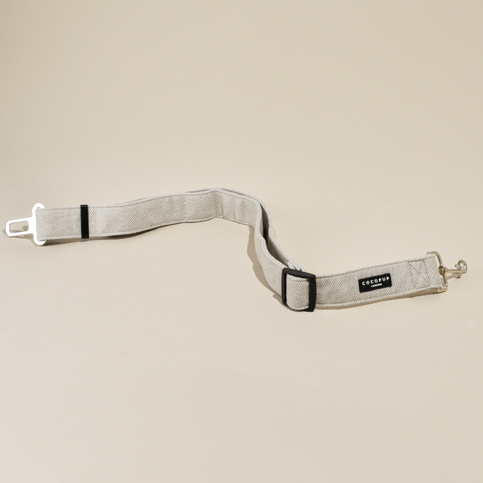 Brown tweed Cocopup London seat belt restraint with metal clips on a beige background.