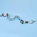 Cocopup London seat belt restraint featuring a playful Dinopaws print with cartoon dinosaurs on a green background.