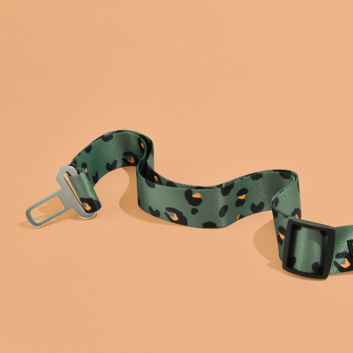 Khaki leopard print seat belt restraint with adjustable harness strap and metal buckle for dogs.