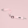 Pink heart-patterned Cocopup London seat belt restraint with metal clips and adjustable strap on a pink background.