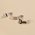 Plain nude Cocopup London seat belt restraint with metal clips on a beige background.