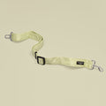 Sage green seat belt restraint with heart patterns, displayed on a light beige background.