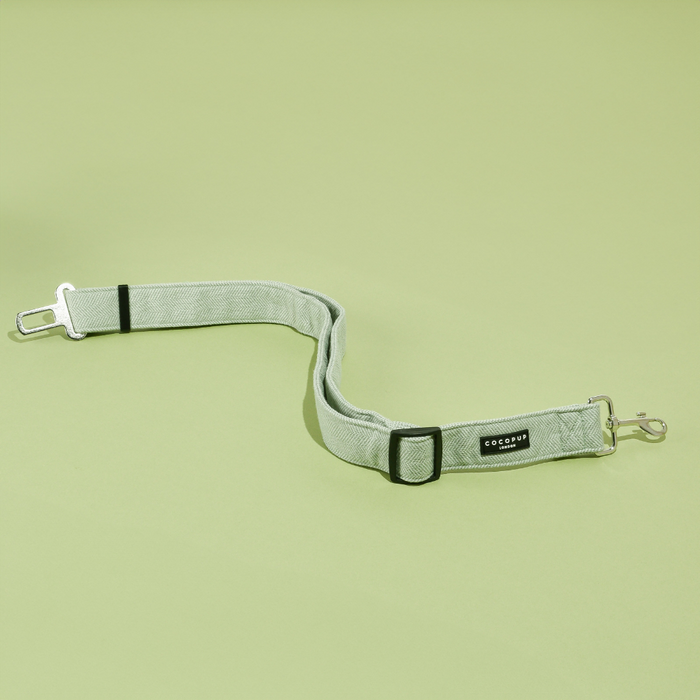 Adjustable dog seatbelt in sage tweed with a silver clip, Cocopup London branding visible.