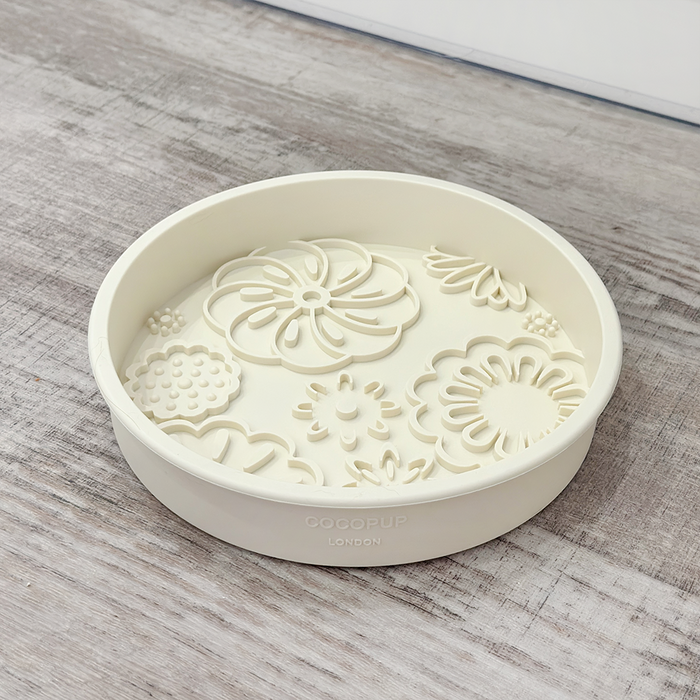 Cream floral-patterned slow feeder dog bowl by Cocopup London on a light wood surface.