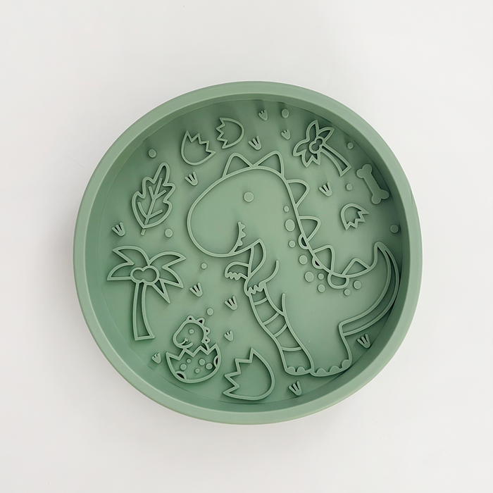 Green round slow feeder dog bowl with molded dinosaur, egg, leaf, and palm shapes.