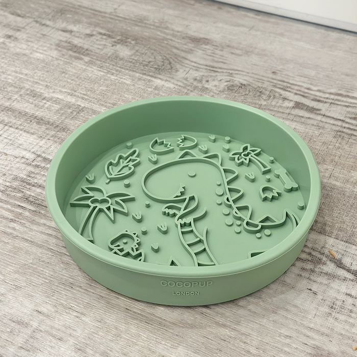 Green silicone slow feeder dog bowl with raised dinosaur and leaf shapes.