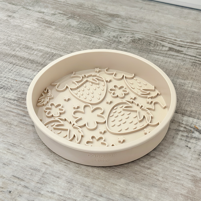 Cocopup London slow feeder dog bowl with strawberry and flower pattern on a light wood surface.
