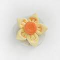 Velvet dog dessert shaped like a daffodil, featuring yellow petals and an orange center.
