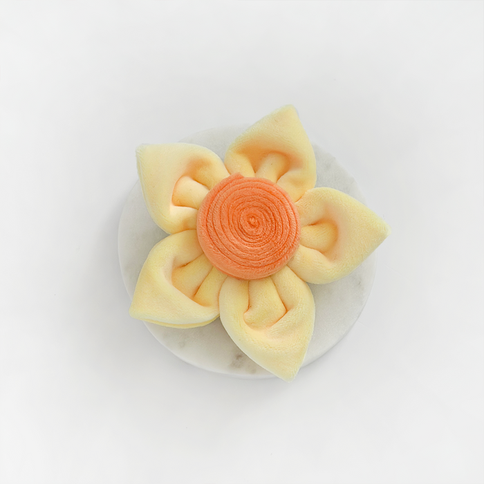 Velvet dog dessert shaped like a daffodil, featuring yellow petals and an orange center.