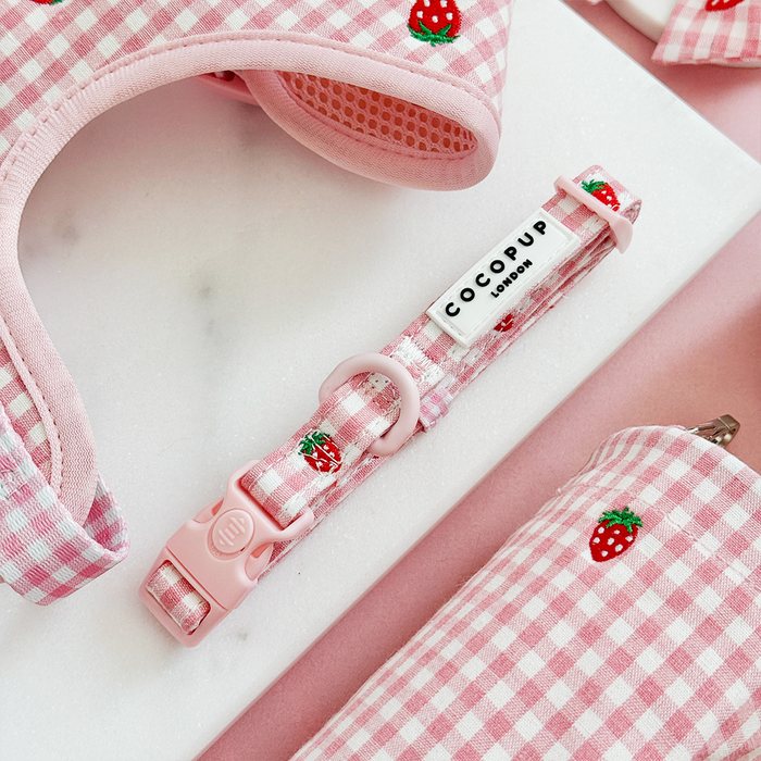 Pink and white strawberry print dog collar with safety lock, matching accessories visible, on a white background.