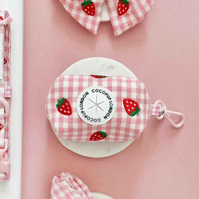 Strawberry-print Cocopup London poop bag holder on a pink and white background.