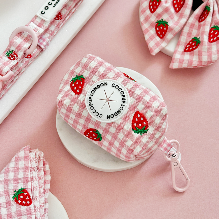Pink gingham dog poop bag holder by Cocopup London, displayed on a pink background.