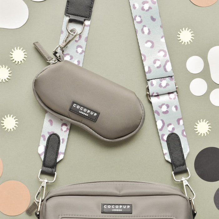 Mocha sunglasses case with leopard print straps on a sage green background.