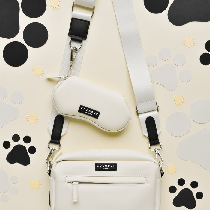 Cocopup London dog walking bag with paw print pouch next to an oyster white sunglasses case on a cream surface.