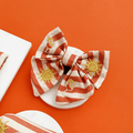 A orange and beige stripe dog sailor bow tie, with embroidered drink and sun graphics.
