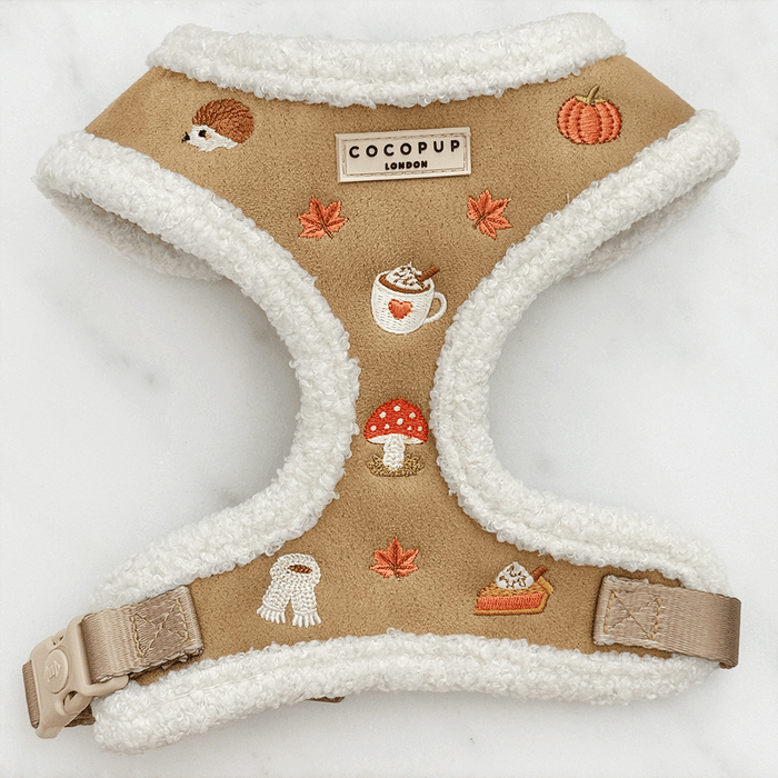 Brown dog harness with white sherpa trim and autumnal-themed embroidery of pumpkins, leaves, a coffee cup, and mushrooms.