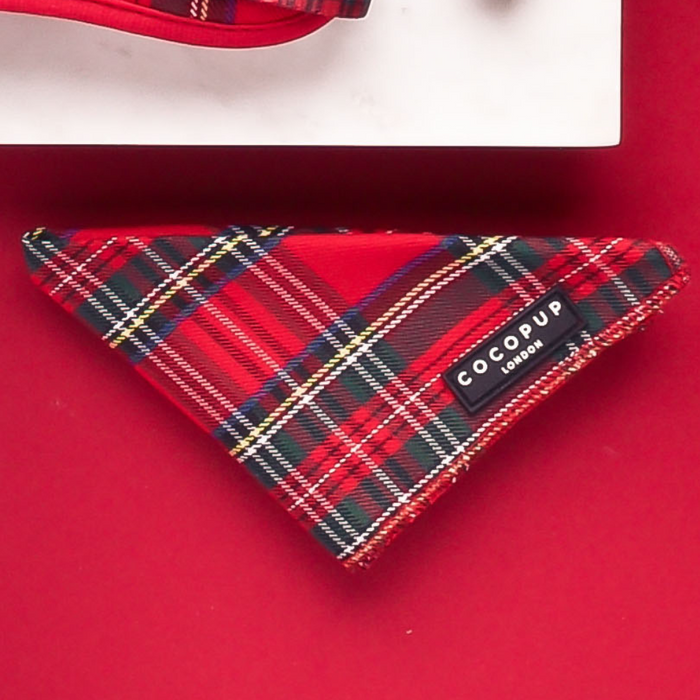 Red tartan Cocopup London dog bandana displayed on a matching red surface.