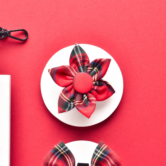 Tartan fabric flower accessory with red and green plaid pattern, designed to attach to a dog collar.
