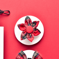 Tartan fabric flower accessory with red and green plaid pattern, designed to attach to a dog collar.