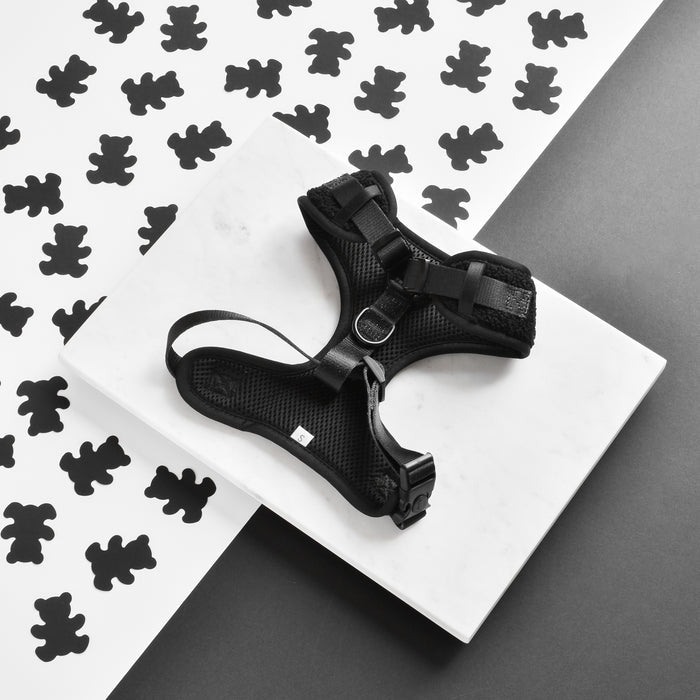 Black adjustable dog harness with teddy bear pattern by Cocopup London on a white marble background.