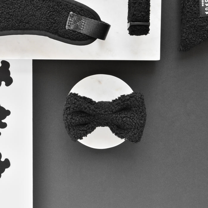 Cocopup London Teddy Bow Tie Baloo in soft beige teddy material, shown on a round white surface with monochrome objects nearby.