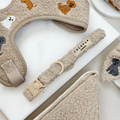 Adjustable beige dog collar with embroidered dogs, matching harness, leash, and bag in soft mocha fabric.
