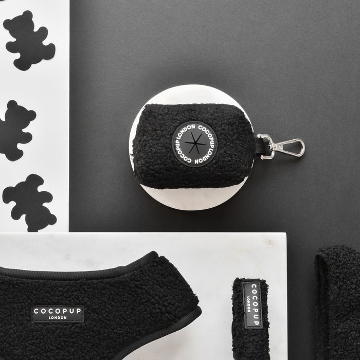 Black Cocopup London Teddy poop bag holder, harness, leash, and treat pouch in black on a white marble background.