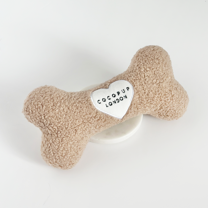 Beige boucle bone-shaped dog toy with a white heart patch.