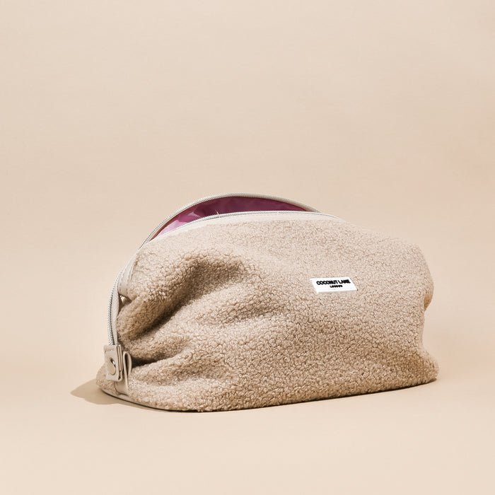Tan fluffy expandable makeup bag with pink interior and a white Cocopup London label.