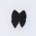 Fluffy black textured pet bow tie with a sailor-style shape, displayed on a plain white background.