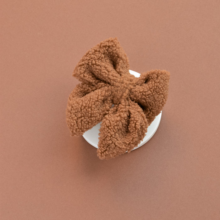 Cocopup London Teddy Sailor Bow Tie in Paddington, fluffy beige fabric, shown on a white round base against a brown background.