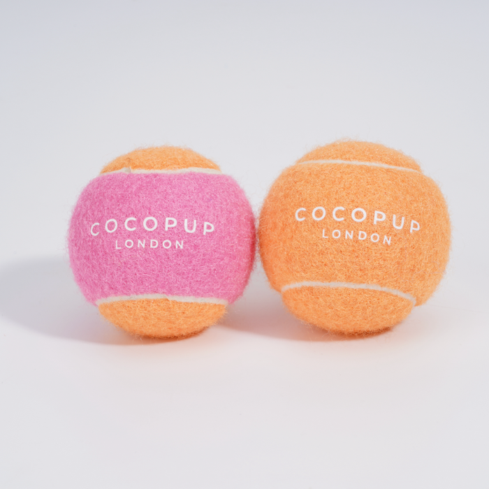 Two tennis balls in pink and orange with Cocopup London printed on each.