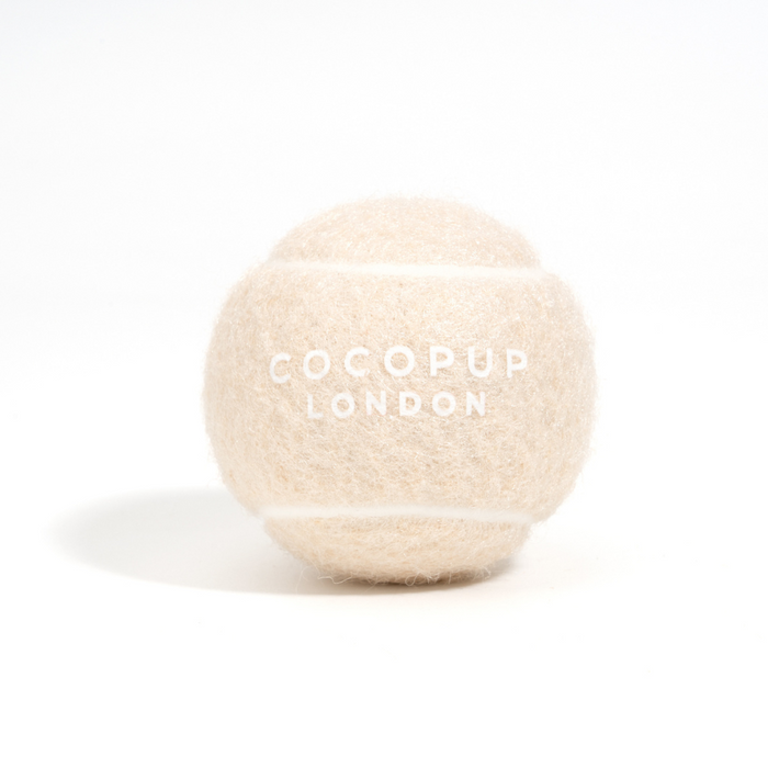 Cream-colored Cocopup London tennis ball with logo, displayed on a white background.