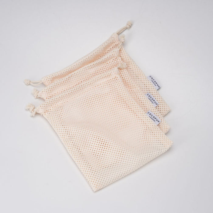 Stack of four cream mesh Cocopup London Tennis Ball Bags, each featuring a visible white label.
