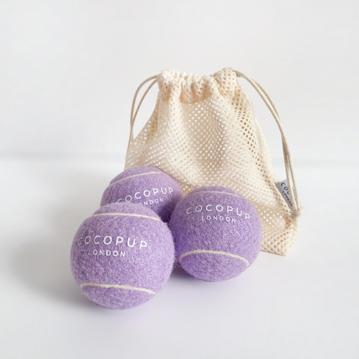 Three purple Cocopup London tennis balls with a white mesh bag for dogs.