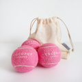 Three pink Cocopup London tennis balls with a cream mesh bag on a white background.