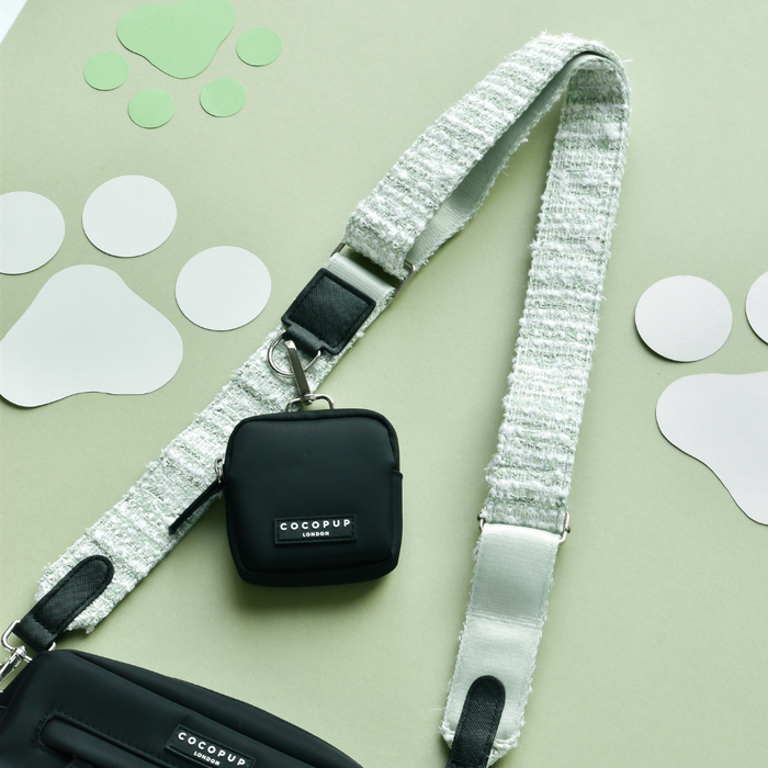 Green textured tweed bag strap with gold hardware, shown on a matcha background with white paw print motifs.