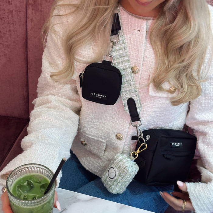 Woman in a white textured jacket holds a matcha drink with a beige Cocopup London bag and green tweed bag strap.