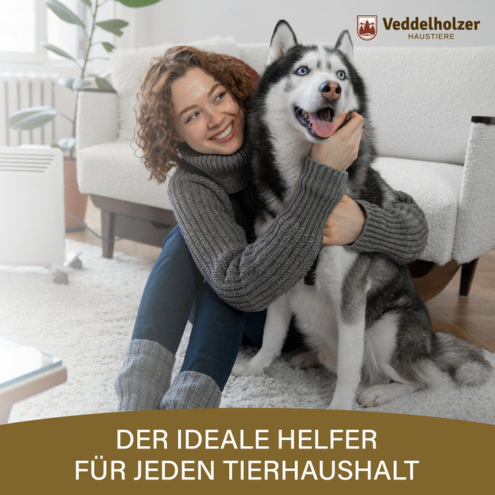 Frau mit Locken umarmt einen Husky auf einem weißen Teppich im Wohnzimmer – Bildtext „Der ideale Helfer für jeden Tierhaushalt“